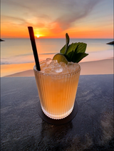 Mai Tai cocktail made using mizzica liqueur agains a beach sunset background