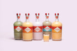 Set of five Mizzica liqueur bottles with different colored labels on a light purple background