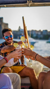 People on a boat with ionico gin drinks and lemon slices, enjoying a sunny day.
