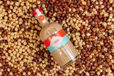 Bottle of Mizzica hazelnut liqueur on a bed of hazelnuts