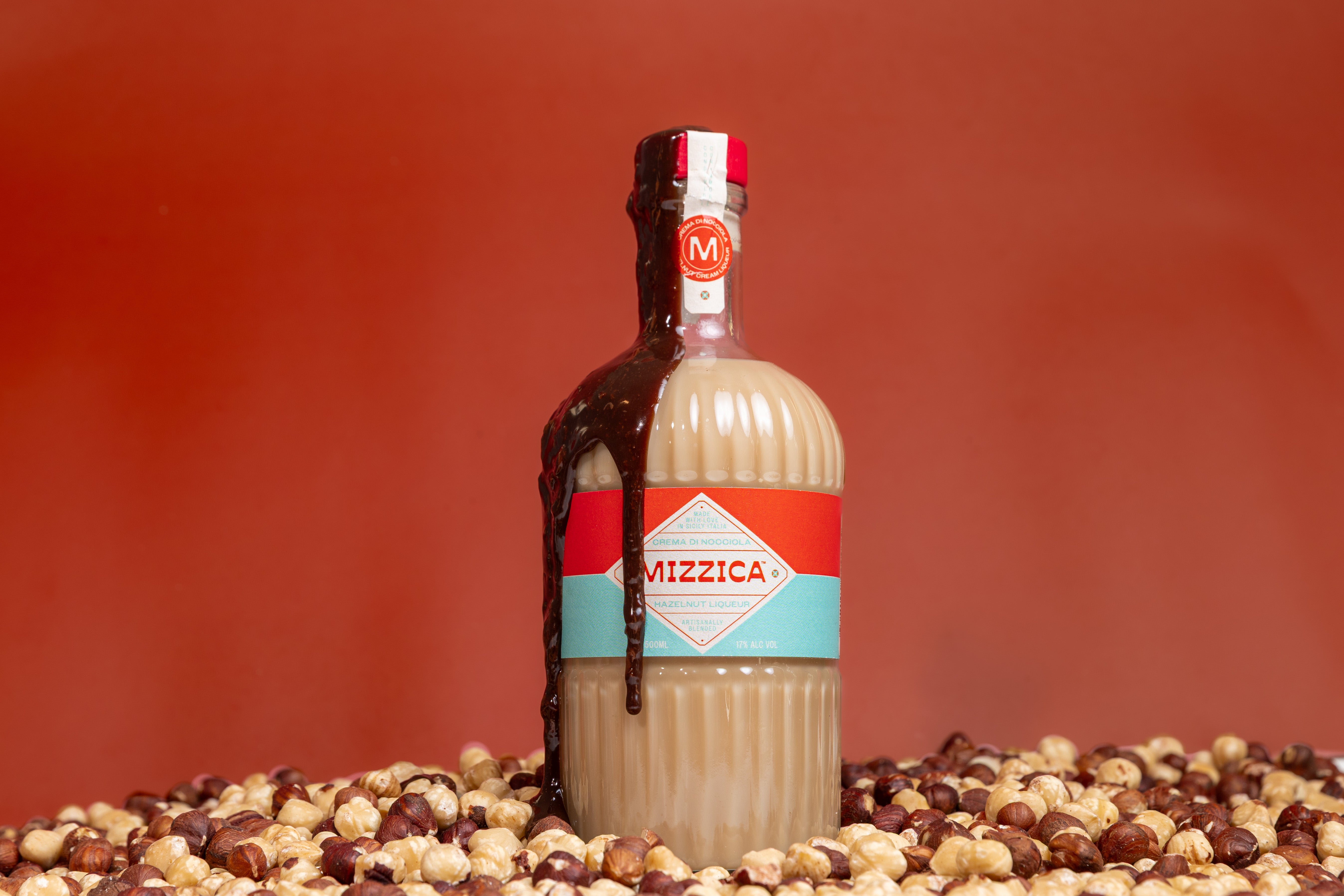 Bottle of Mizzica hazelnut liqueur on a red background