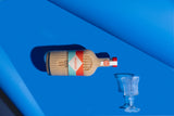Bottle of Mizzica hazelnut liqueur with a glass on a blue background