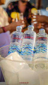 Three bottles of Ionico water on a table with blurred people in the background