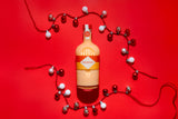 Bottle of Mizzica rockmelon liqueur on a red background with decorative lights