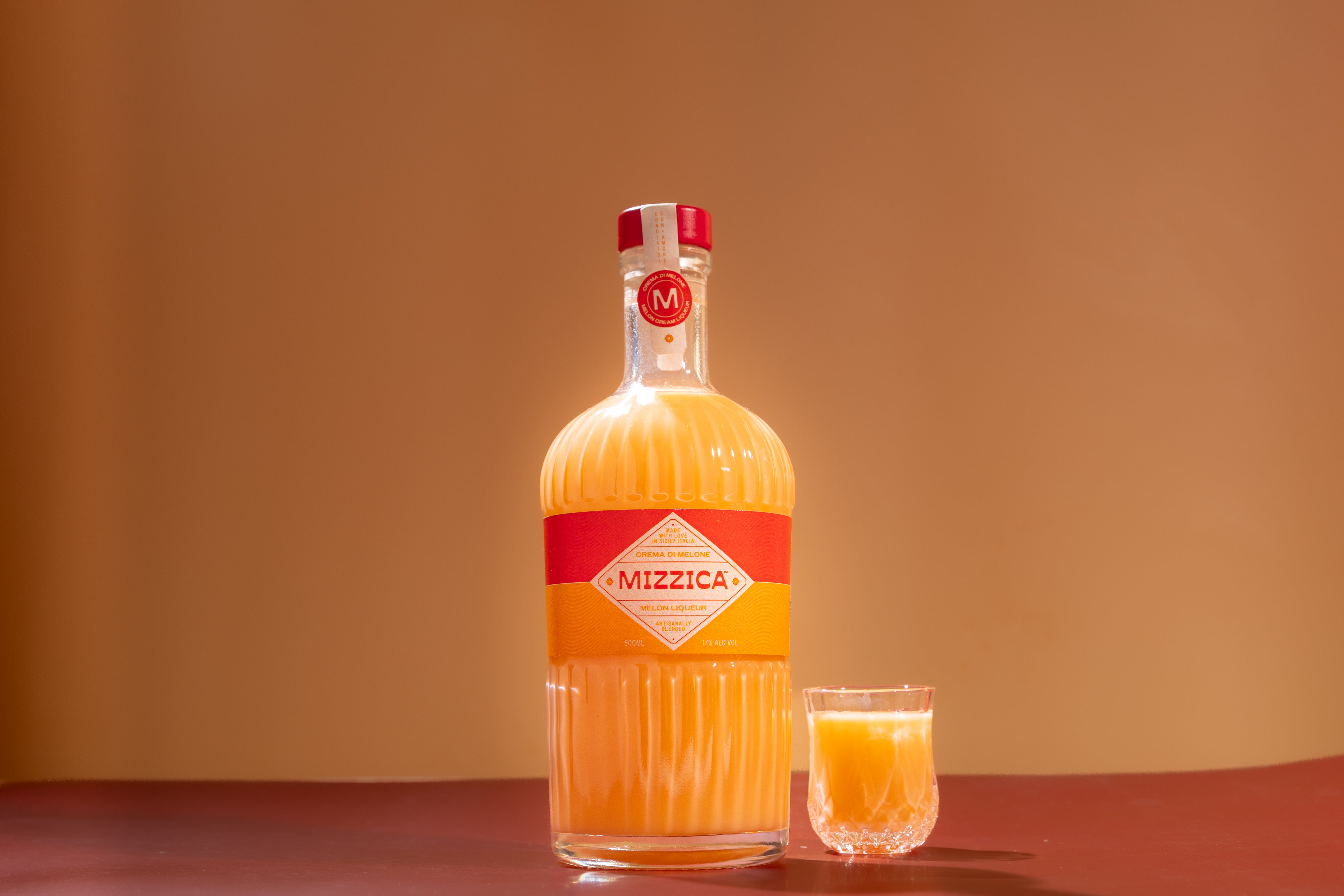 Bottle and glass of Mizzica rockmelon liqueur on a brown background