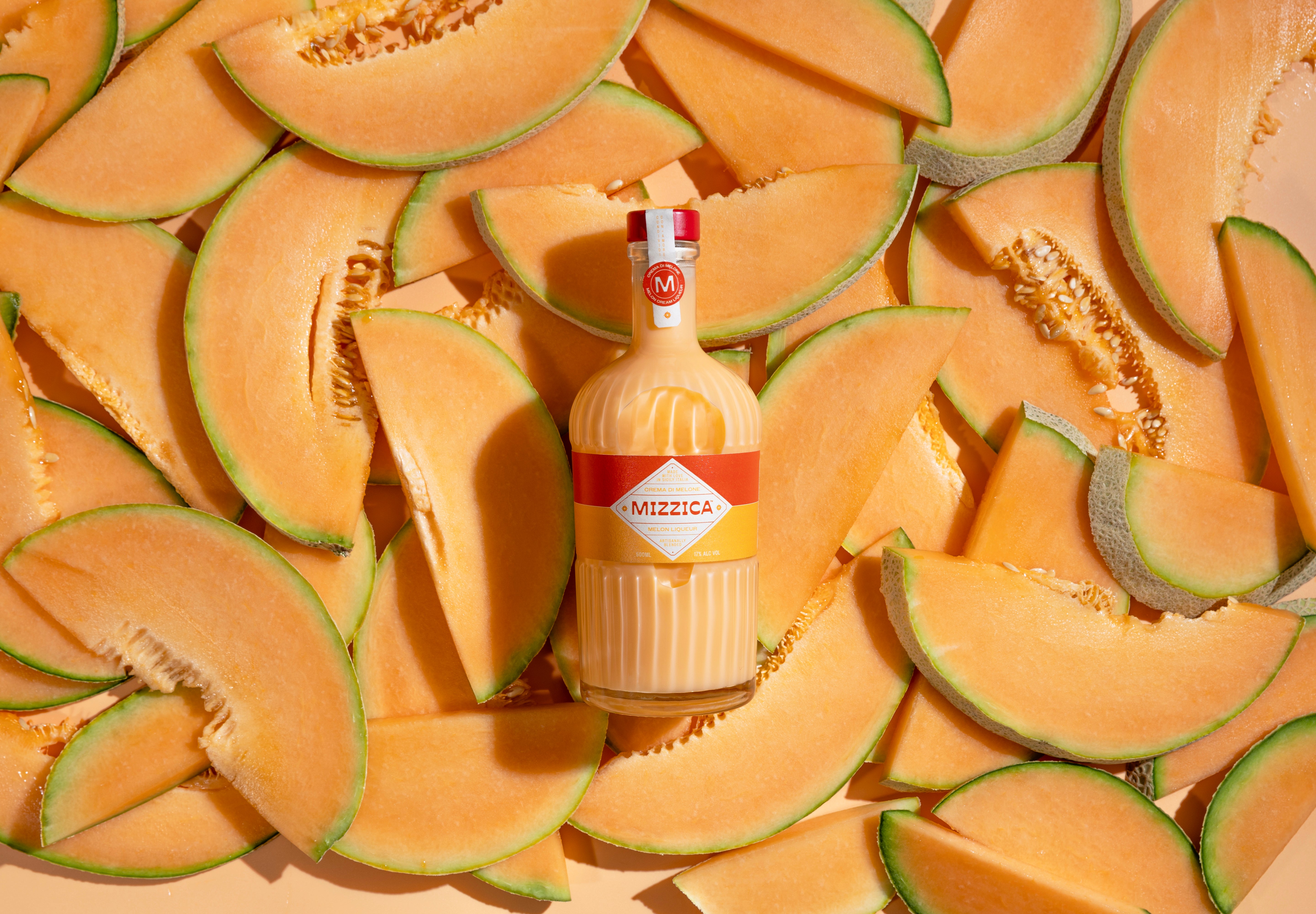 Bottle of Mizzica rockmelon liqueur surrounded by sliced melon