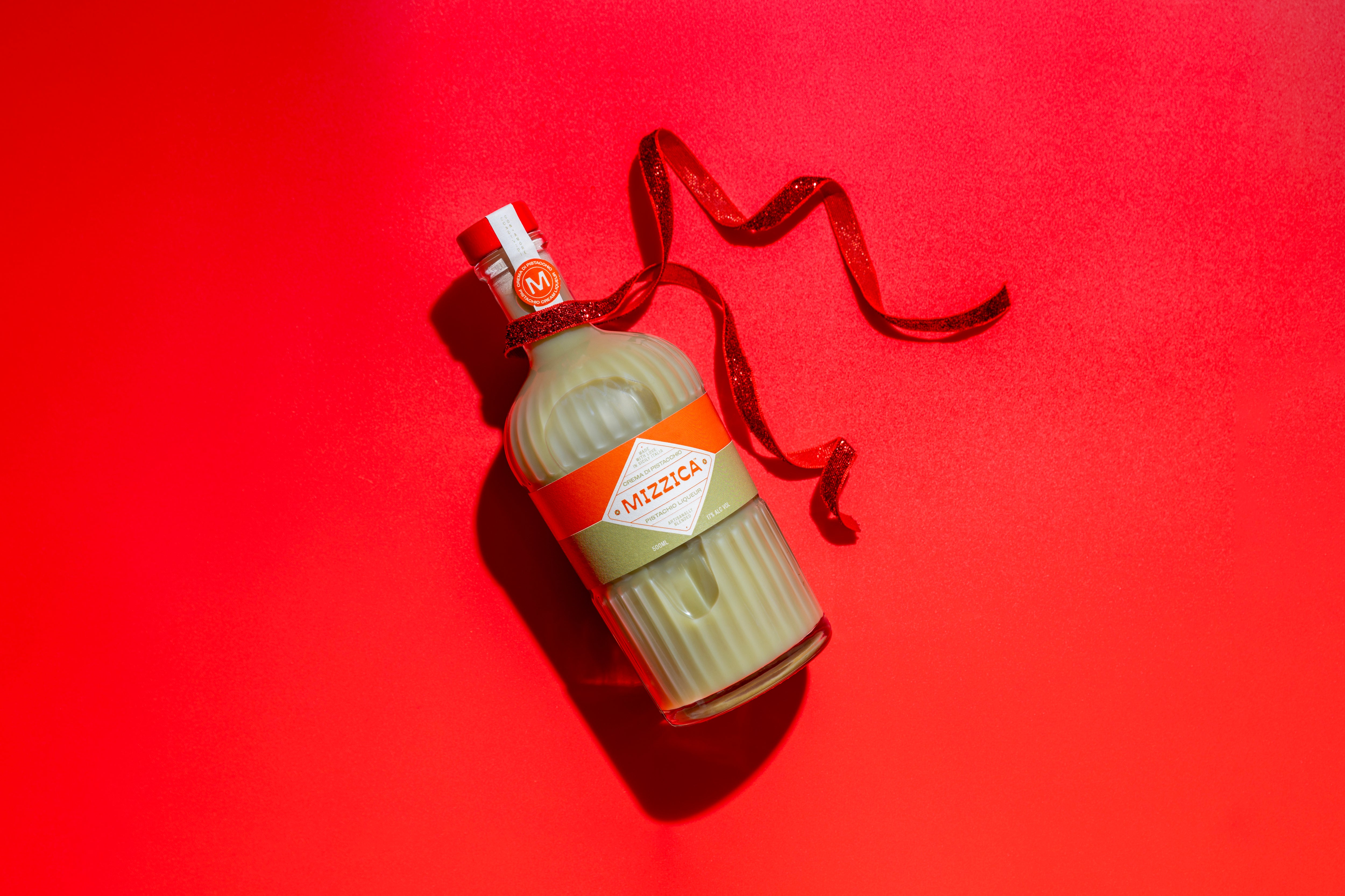 Mizzica pistachio liqueur bottle with a red ribbon on a red background