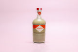 Bottle of Mizzica pistachio liqueur on a pink background
