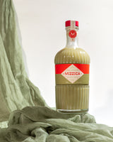 Bottle of Mizzica liquor on a light green fabric background