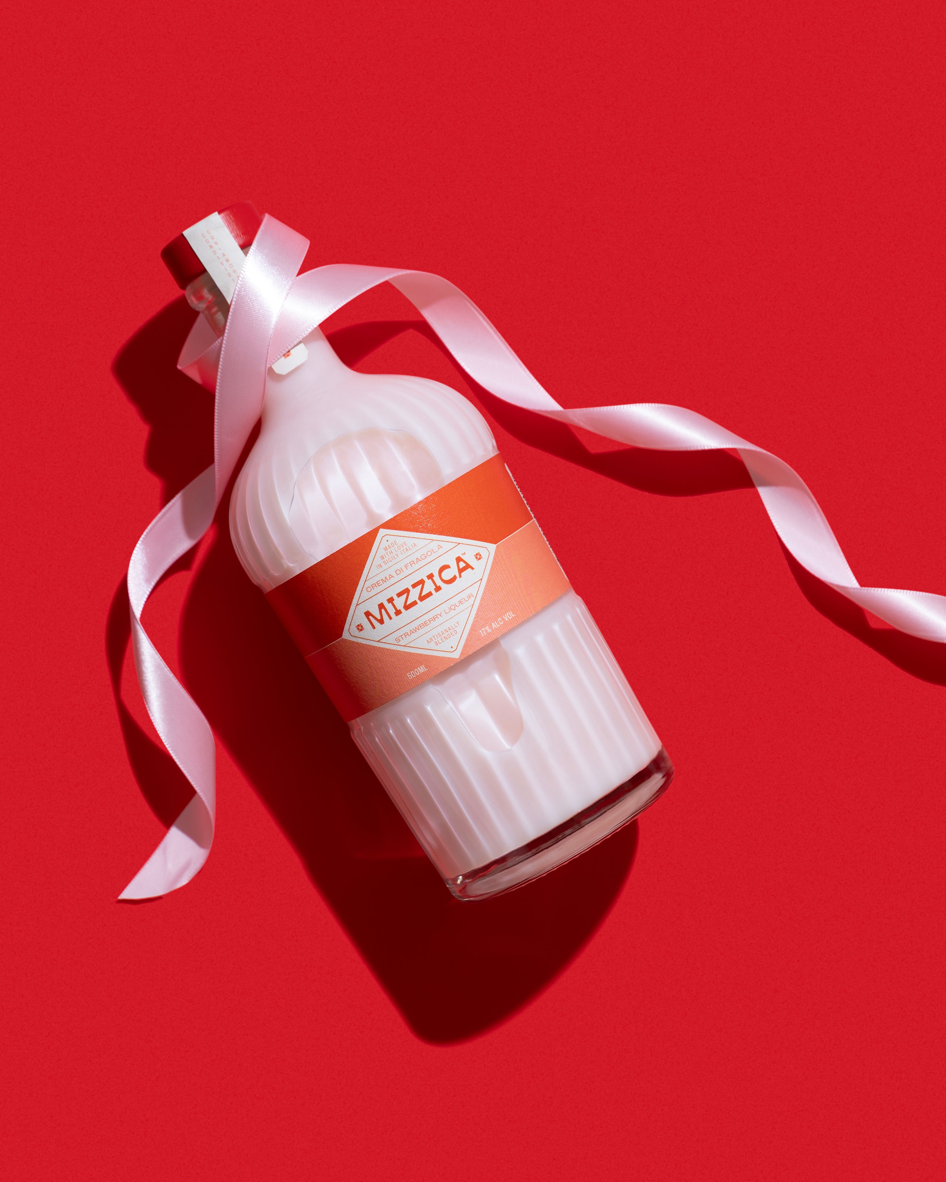 Mizzica strawberry liqueur bottle with a white ribbon on a red background